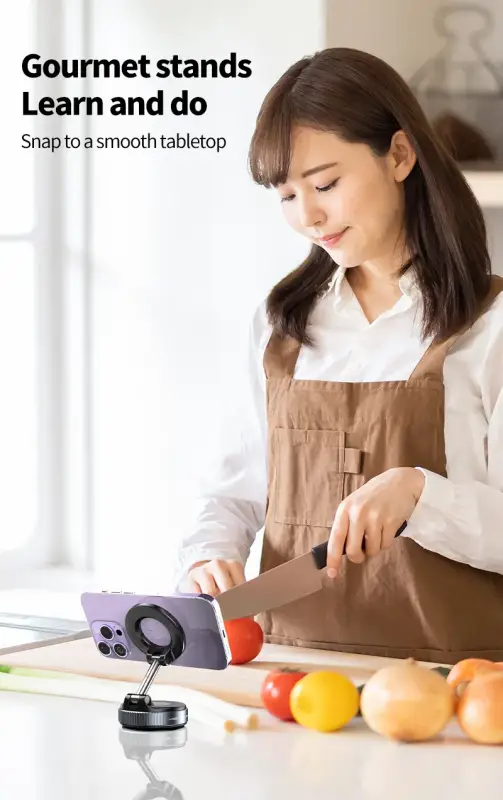 Woman in a kitchen using a smartphone stand with text 'Gourmet stands Learn and do Snap to a smooth tabletop'.