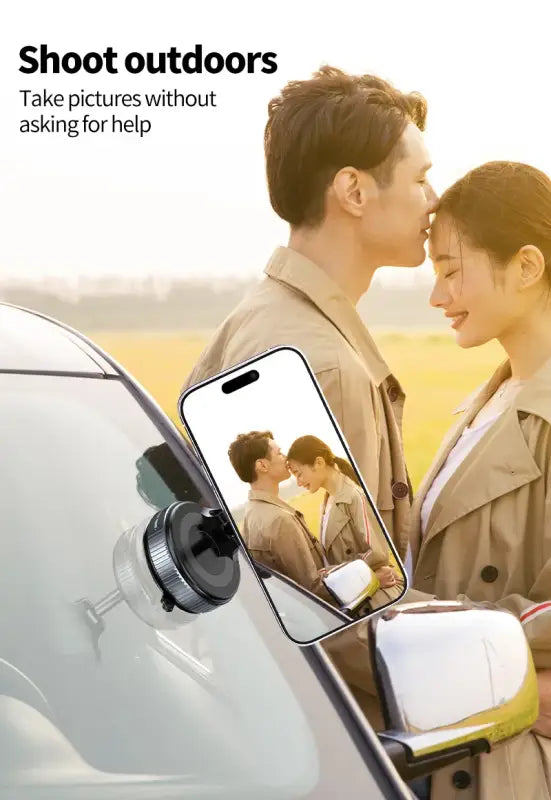 Phone mounted on a car dashboard with a couple in the background, showing a phone screen with a photo of the couple.
