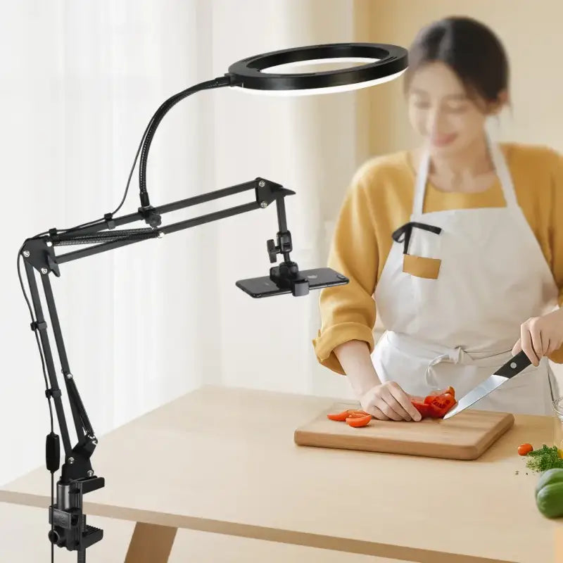 Person cutting vegetables with a magnifying lamp on a table