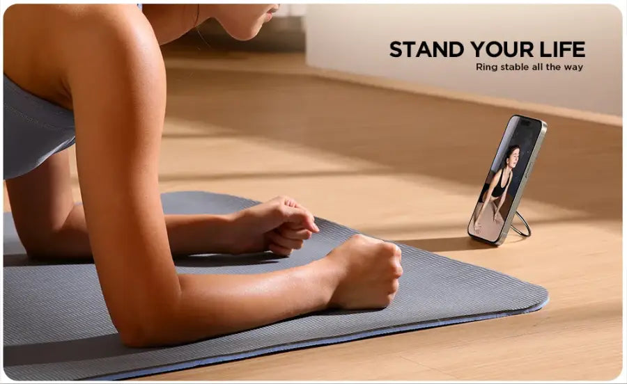 Person on a yoga mat with a phone displaying a fitness app, and 'Stand Your Life' text in the background.