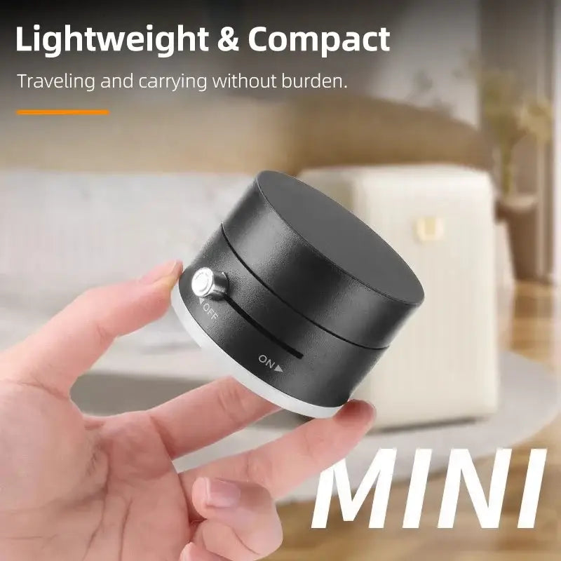Hand holding a small black device with 'MINI' text, blurred background